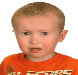 Zdjęcie przedstawia chłopca w pomarańczowej koszulce