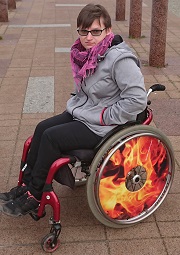 Zdjęcie przedstawia kobietę na wózku w okularach