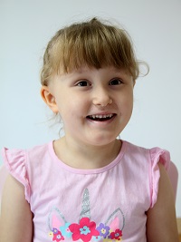 Zdjęcie przedstawia dziewczynkę uśmiechnięta