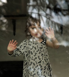 Zdjęcie przedstawia chłopca za oknem