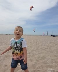 Zdjęcie przedstawia chłopca uśmiechniętego z latawcem