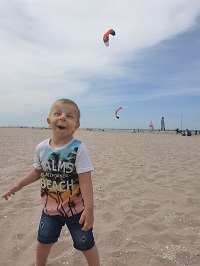 Zdjęcie przedstawia chłopca uśmiechniętego z latawcem