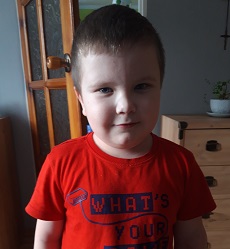 Zdjęcie przedstawia chłopca w czerwonej koszulce