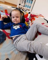 Zdjęcie przedstawia chłopca z słuchawkami na uszach