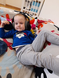 Zdjęcie przedstawia chłopca z słuchawkami na uszach