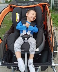 Zdjęcie przedstawia chłopca uśmiechniętego w wózku