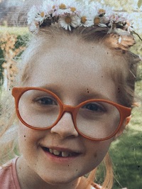 Zdjęcie przedstawia dziewczynkę wiankiem na głowie w okularach