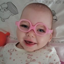 Zdjęcie przedstawia dziewczynkę uśmiechnięta w okularach