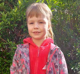 Zdjęcie przedstawia dziewczynkę z różowa kurteczką