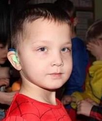 Zdjęcie przedstawia chłopca z aparatem w uchu