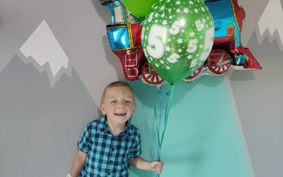 Zdjęcie przedstawia chłopca z balonami