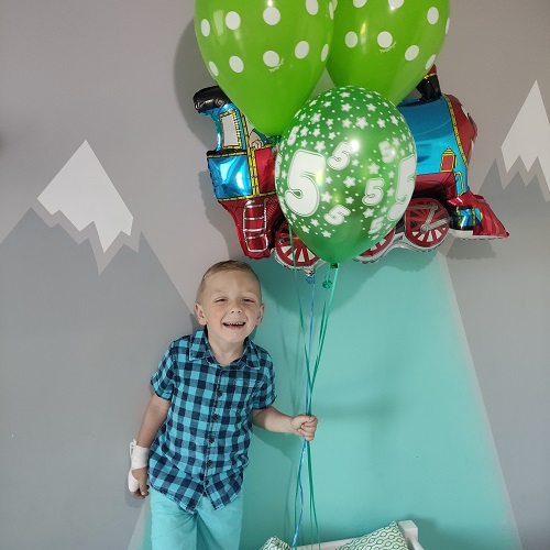 Zdjęcie przedstawia chłopca z balonami
