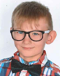 Zdjęcie przedstawia chłopca z muchą w okularach