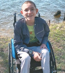 zdjęcie przedstawia chłopca na wózku nad wodą