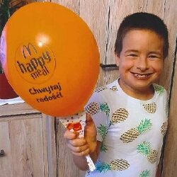 Zdjęcie przedstawia chłopca uśmiechniętego z balonem