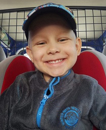 Zdjęcie przedstawia chłopca uśmiechniętego w czapce z daszkiem