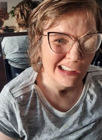 Zdjęcie przedstawia kobietę uśmiechniętą w okularach